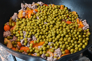 aggiungere i piselli nel ragù di pomodorini e carne