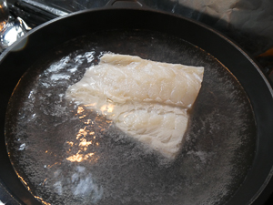 Sciacquare il pezzo di baccalà (mussillo) e lessarlo in acqua bollente