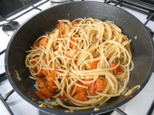 mantecare gli spaghetti con capperi, pomodoro e acciughe