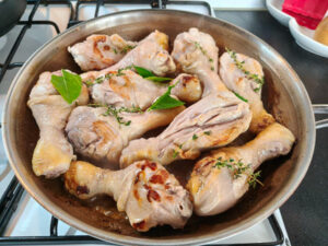 cuocere i fusi di pollo con 2 spicchi di aglio, l’olio, il succo filtrato della marinata, il burro, il timo fresco, la foglia spezzettata del limone